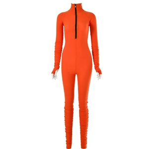 Detail of orange ribbed catsuit featuring a black half-zip collar and thumbhole cuffs