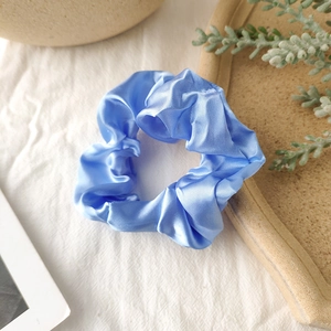 Detail of royal blue satin scrunchie showing glossy silk texture and delicate pleats