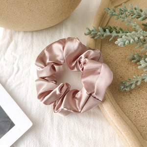 Detail of elegant dusty rose satin scrunchie with smooth silk texture and soft sheen