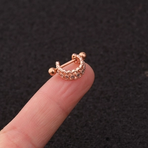 Close-up of rose gold U-shaped ear stud with zircon stones on a dark background