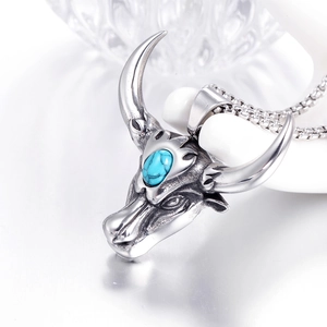 Macro shot of a silver bull head pendant featuring a turquoise stone and box chain detail