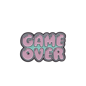 Macro detail of Game Over enamel pin with pink and green colors and metal edge