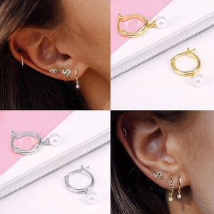 Detail of S925 silver pearl drop earrings and snake-shaped studs on model ear
