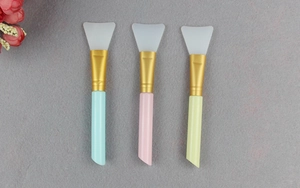 Detailed view of three silicone face mask brushes with soft white tips and colorful handles