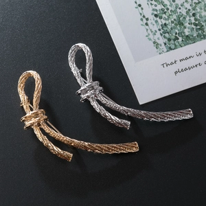 Artistic knotted twist bow brooch in gold and silver alloy finish on dark background