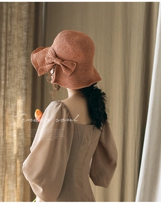 Vue de dos d'une femme portant un élégant chapeau de soleil en paille marron avec nœud