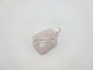 Macro detail of wire-wrapped pink rose quartz crystal pendant in polished silver finish
