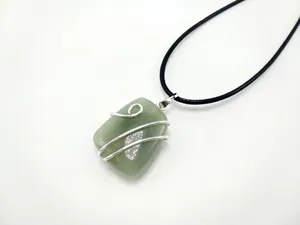 Detailed shot of green gemstone pendant with silver wire wrap and black cord necklace