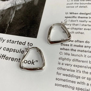 Macro detail of geometric S925 sterling silver earrings on fashion magazine background