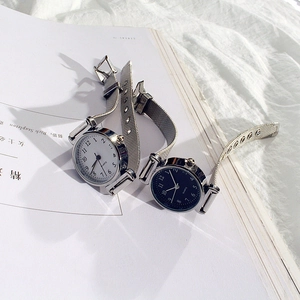 Close-up of minimalist quartz watches with silver Milanese mesh straps and numeric dials