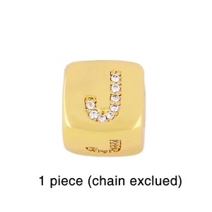 Detail of gold cube charm featuring crystal-encrusted letter J and polished metal finish