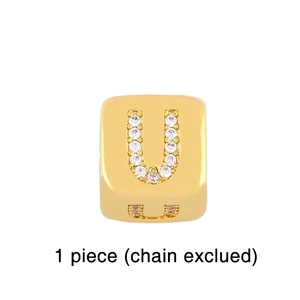 Macro shot of a gold cube charm with letter U and micro-set cubic zirconia stones