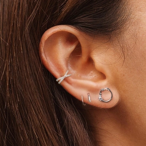 Detail der silbernen S925 Earcuff mit Kreuzmuster und Diamanten sowie kleinen Creolen