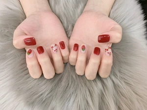 Close-up of strawberry and cherry nail stickers on short round red press-on nails