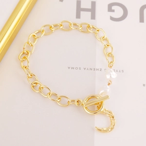 Close-up of gold OT buckle chain bracelet with baroque pearls and moon pendant
