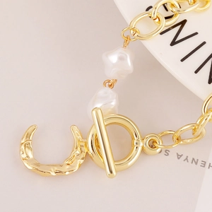 Detailed close-up of baroque irregular pearl bracelet with moon charm and golden toggle clasp