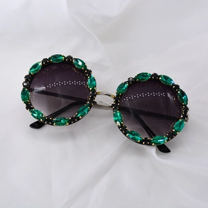 Detailed view of round oversized sunglasses with marquise green crystals and silver bridge