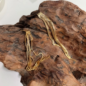 Detail shot of 925 silver long gold tassel earrings with multiple box chains on wood