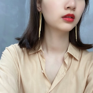 Detailed view of long gold tassel earrings in 925 sterling silver worn by a model