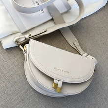 Détail d'un sac besace demi-lune blanc cassé minimaliste avec finitions dorées chics