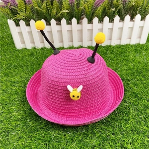 Pink kids straw sun hat with cute bee design and antenna pom poms for beach wear