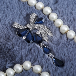 Gros plan sur la broche nœud vintage avec cristaux goutte bleu foncé et glands en argent