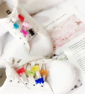 Close-up of colorful translucent gummy bear charms on white sneakers with various colors