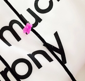 Macro shot of a pink gummy bear resin charm on a black cord against a white fabric bag