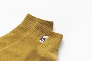 Close-up of mustard yellow cotton blend socks with a small white rabbit embroidery detail