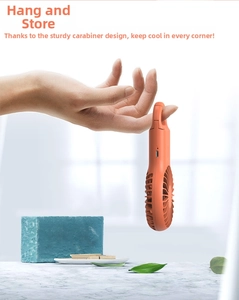 Detail of portable orange mini fan with integrated carabiner hook and USB charging port