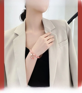 Close-up of pink crystal beaded bracelet with strawberry charm on a model's wrist