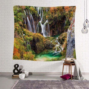 Detail of bohemian nature tapestry with waterfall landscape on a white brick wall
