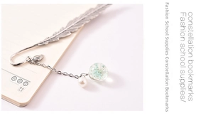 Close-up of silver metal feather bookmark with dried flower glass ball on a notebook