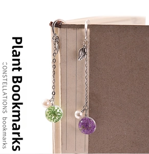 Exquisite metal bookmarks with real dried flower glass balls and leaf pendants on a book