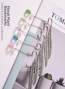 Macro view of five feather-shaped metal bookmarks featuring resin dried flower charms