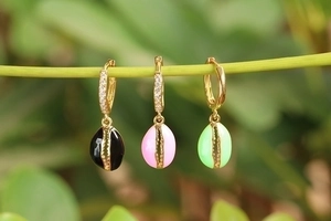 Colorful enamel oval hoop earrings in black pink and green on a natural plant stem