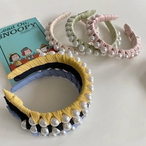 Close-up of woven fabric headbands decorated with polished pearls in diverse colors
