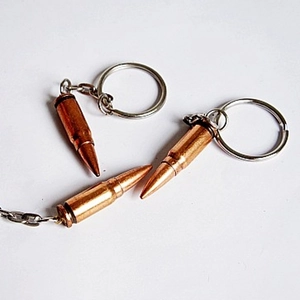 Detailed view of three metallic bullet-shaped keychains with polished copper finish