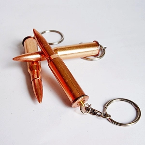 Macro shot of two realistic brass-colored metal bullet-shaped keychains on white background