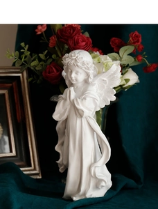 Close-up of white praying angel resin sculpture against green velvet background