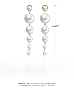 Macro detail of elegant long drop earrings featuring cascading white pearls and gold alloy