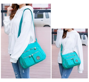 Outdoor shot of a teal nylon crossbody bag with multiple pockets and a wide strap