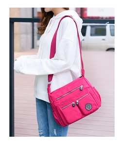 Detailed view of magenta waterproof nylon bag with multi-pocket design and wide shoulder strap