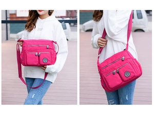 Outdoor street view of a multi-pocket magenta nylon crossbody bag worn by a model
