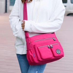 Waterproof rose red nylon crossbody bag with multiple zipper pockets shown on model
