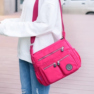 Detail of red nylon crossbody bag with multiple zipper pockets and adjustable wide strap