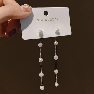 Detail of long pearl tassel earrings featuring vertical gold chains and glossy beads