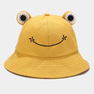 Detail of yellow canvas bucket hat featuring 3D frog eyes and fine embroidered smile