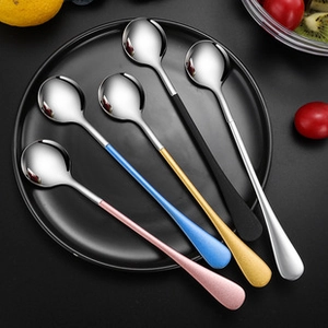 Detailed top view of colorful long-handled stainless steel coffee spoons on a black plate