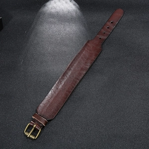 Vintage dark brown cowhide leather bracelet with a retro metal buckle on black background